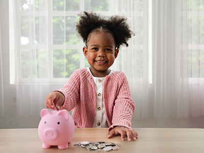 girl putting money into piggy bank