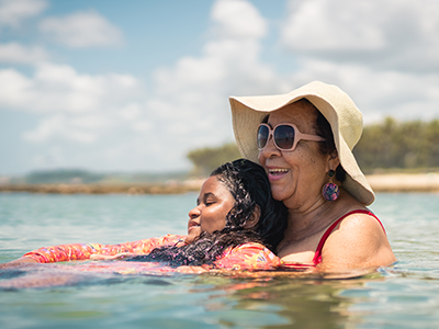 mother holding teenaged daughter while floating in a lake