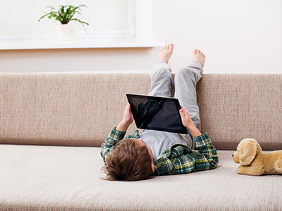 boy lying on couch using tablet