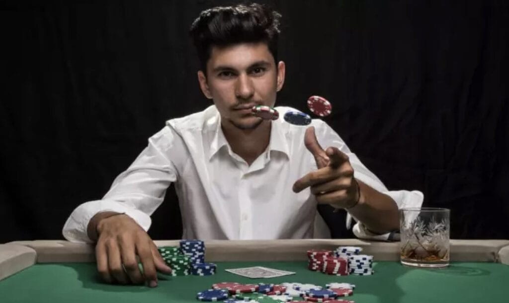 A person in a white shirt sits at a poker table and throws chips.