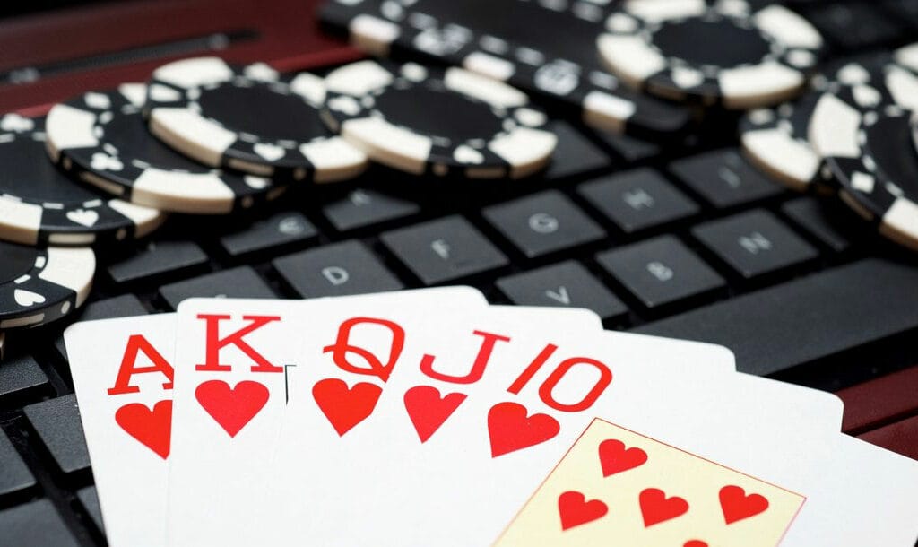 A royal flush sitting on a keyboard surrounded by poker chips.