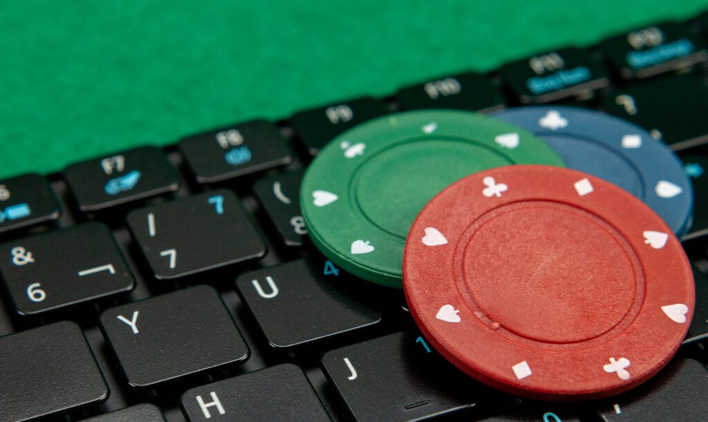 Green, red and blue poker chips on top of a keyboard.