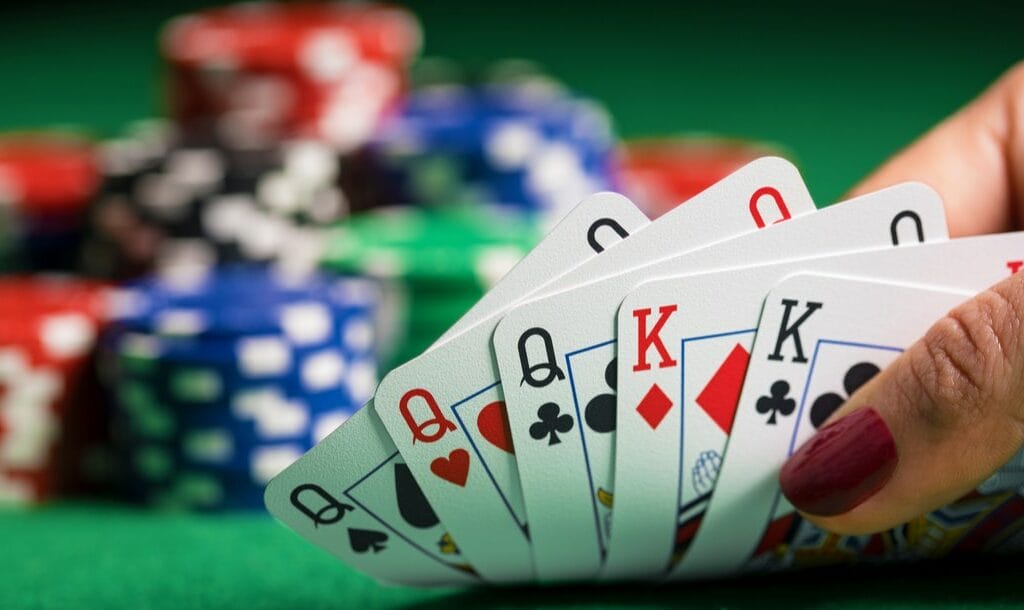 Closeup of poker cards with chips in the background.