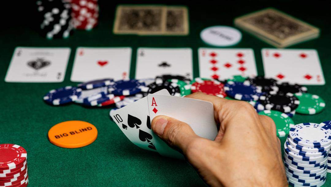 A player with the big blind button looks at their cards during a poker game.