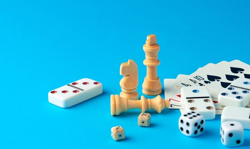 Items for playing chess, poker, and domino on blue background studio shot