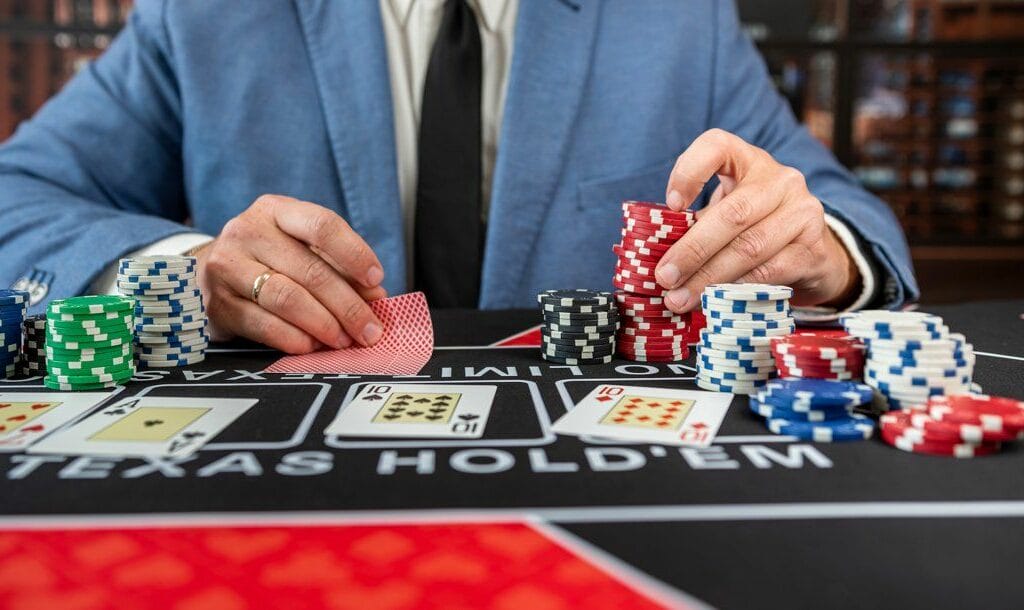 A poker player in a blue suit checking their hole cards while deciding what to bet.