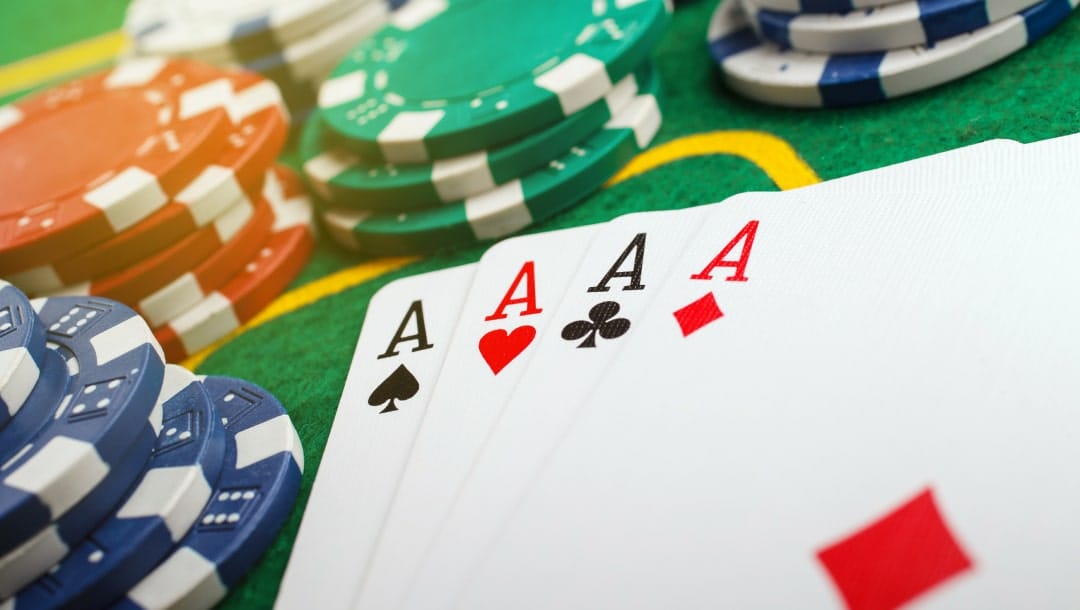 A closeup of a full suit of Aces, blue, red, green, and white poker chips arranged on a poker table.