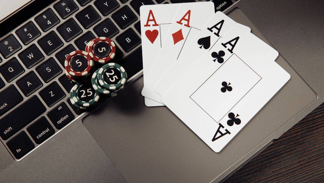 A full suit of Aces, red, and green casino chips arranged on a laptop.