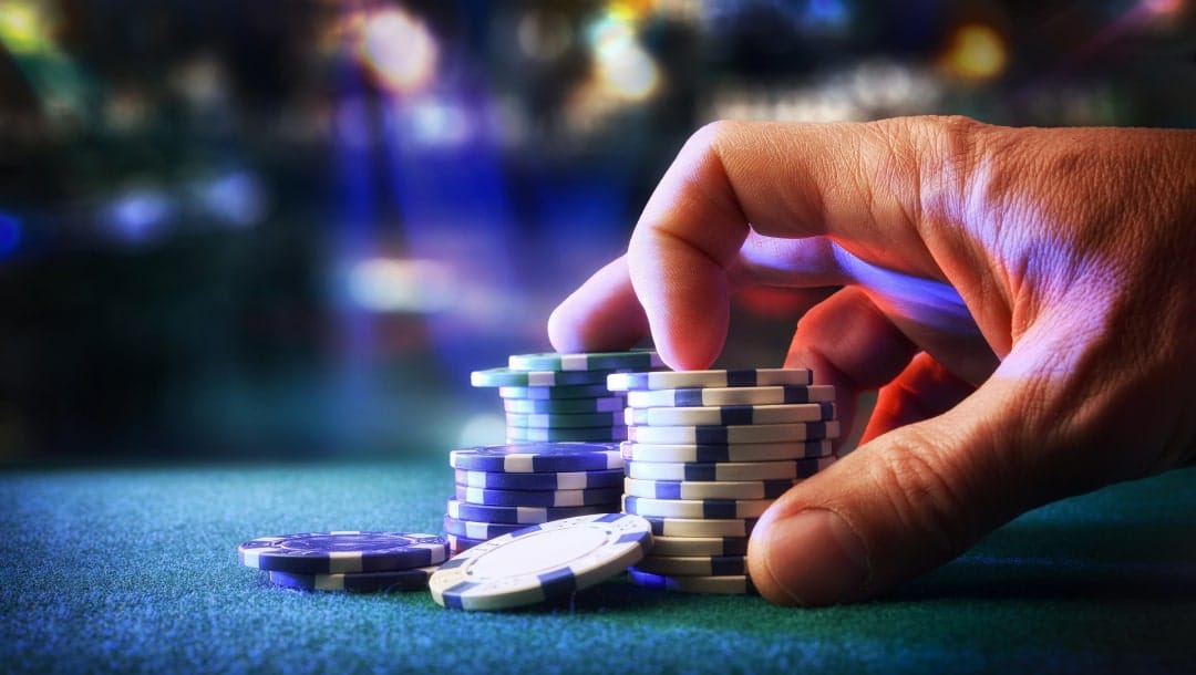 close up of a hand pushing poker chips over a table