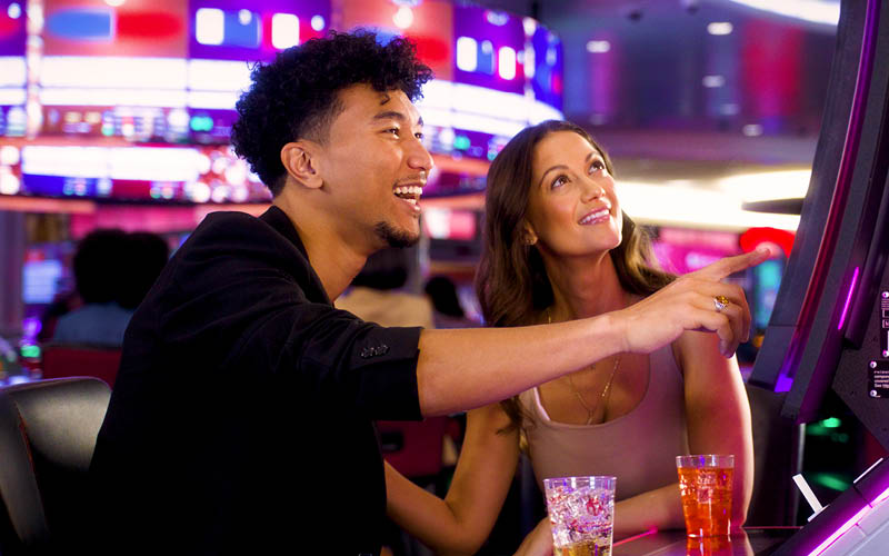 Couple at casino on slot machine.