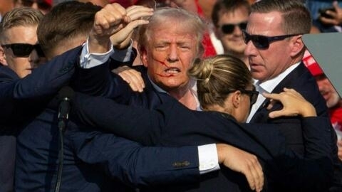 Donald Trump, seen with blood on his face, is surrounded by secret service agents as he is taken off the stage at a campaign event in Butler, Pennsylvania, July 13, 2024.