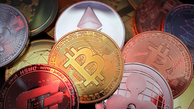 Image shows metallic coins printed with the various logos of popular cryptocurrencies