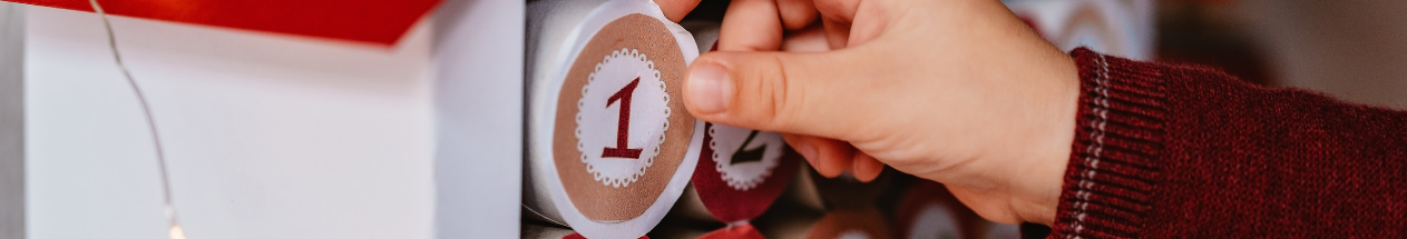 Child's hand opening the first door on a Christmas advent calendar