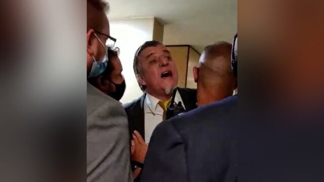 Assessores e auxiliares tentam conter parlamentar do PROS-RS nos corredores da Câmara dos Deputados. Deputado Alexandre Leite (DEM-SP) é acusado por Boca Aberta pelo crime de 'rachadinha' em São Paulo.