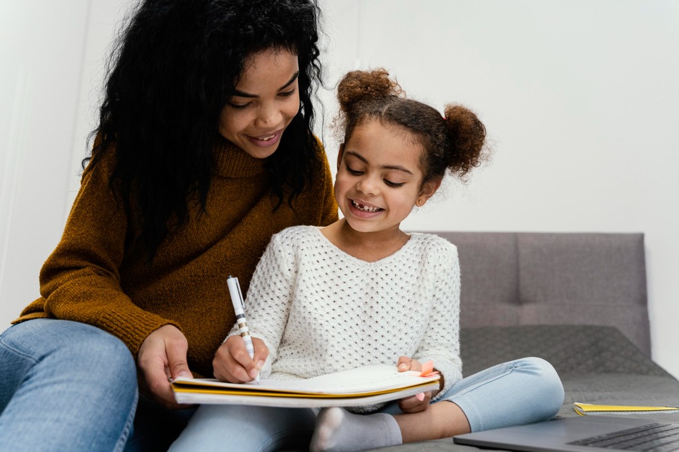 Mãe estudando junto com a filha e ajudando a fazer a lição de casa — Foto: Freepik