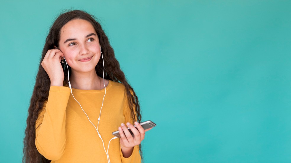 Menina escutando música usando fone de ouvido — Foto: Freepik