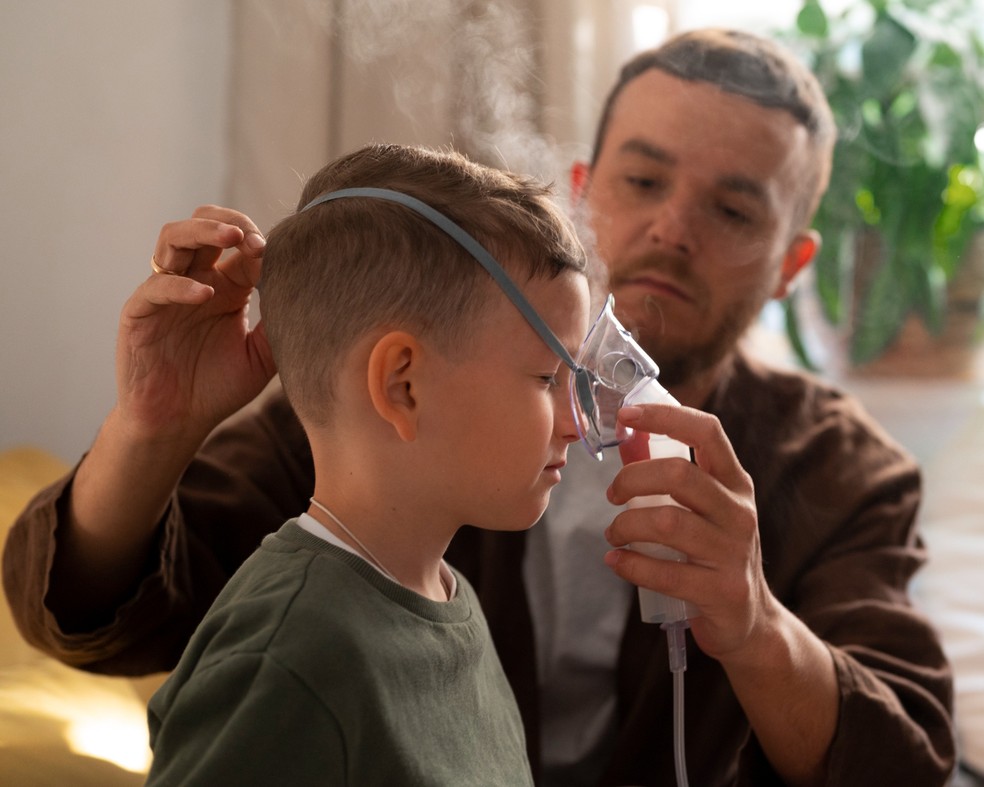 Pai ajudando o filho a fazer inalação — Foto: Freepik