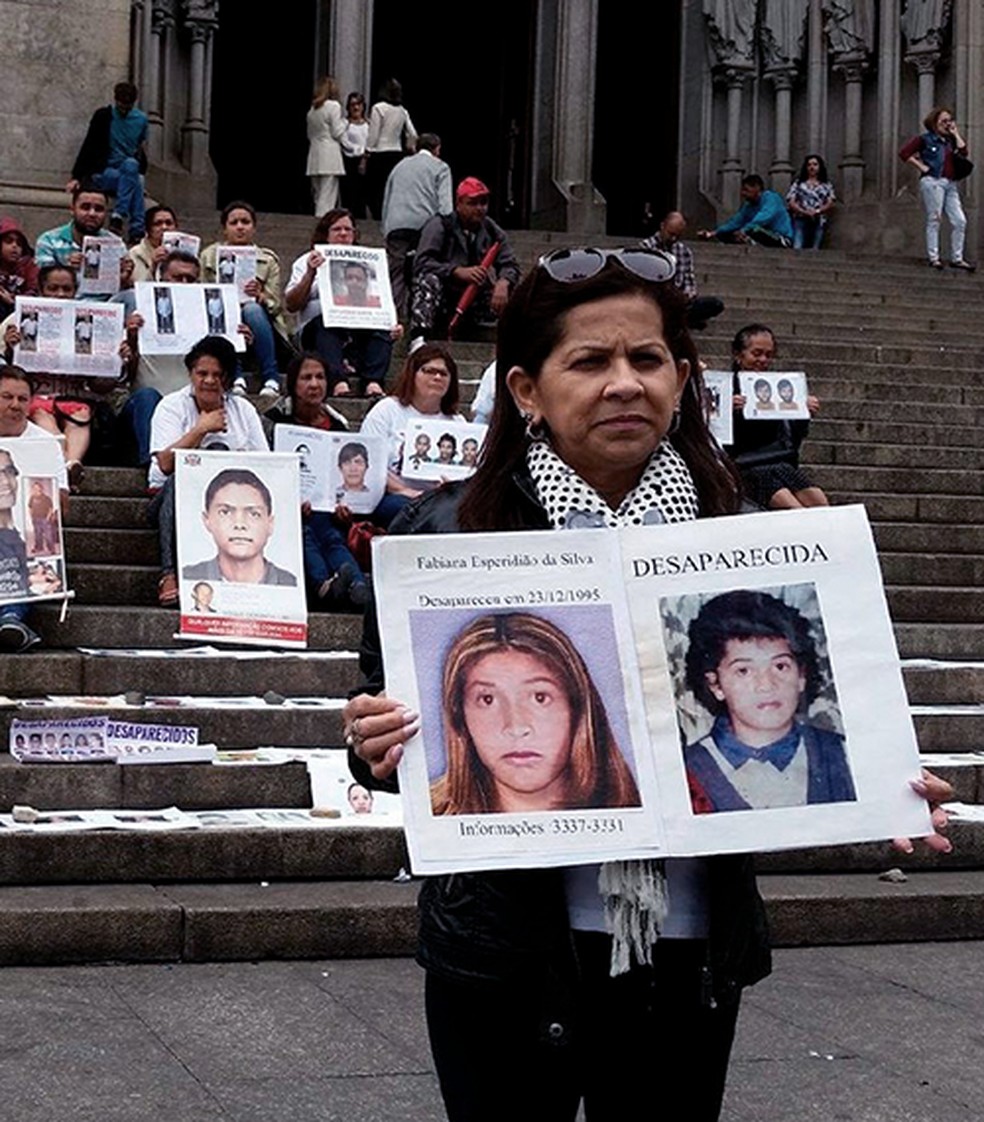 Ivanise na Praça da Sé, mostrando um cartaz com fotos da filha — Foto: Reprodução