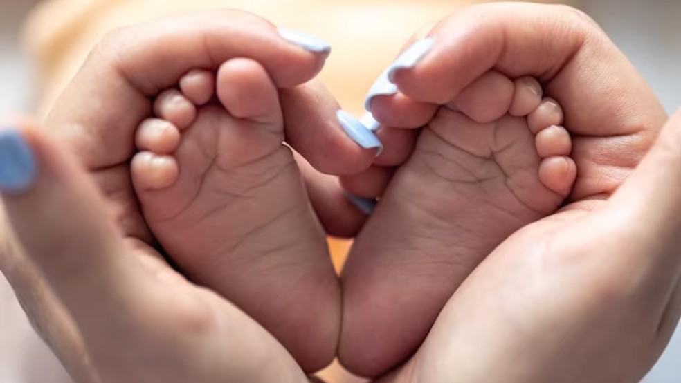 Mãe segurando pés de bebê recém-nascido — Foto: Freepik