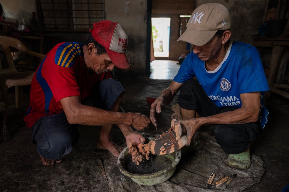 Os ceramistas Hugo Osorio e Pedro Fuentes trabalham em artesanato de barro de estilo pré-colombiano em Momil. — Foto: Foto: Luis ACOSTA / AFP