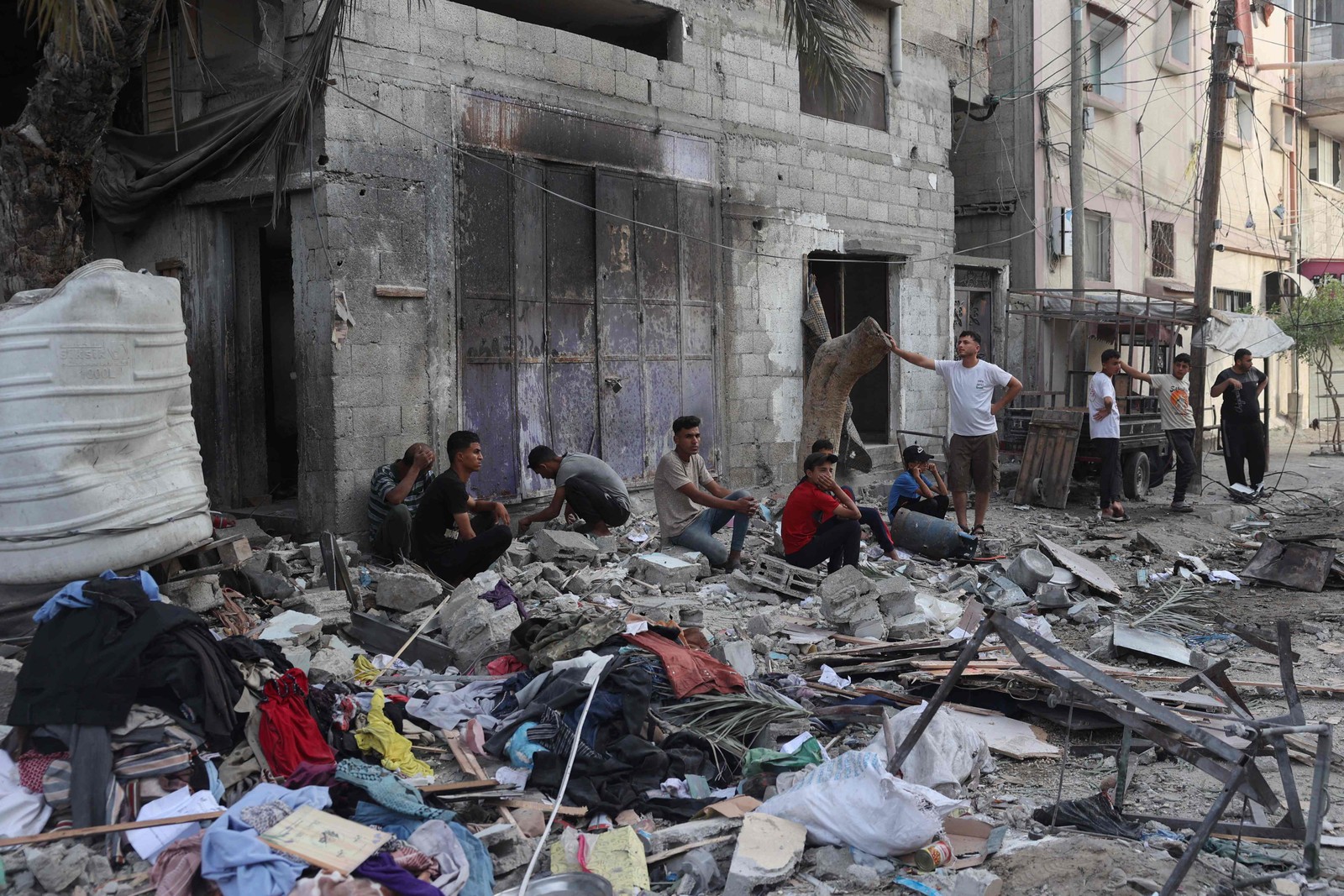 Situação humanitária em Rafah: palestinos sentam-se junto aos escombros de uma casa de família que foi atingida durante bombardeio — Foto: AFP