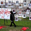 Mulher passa diante de cartazes de mulheres desaparecidas, durante protesto contra a violência de gênero na Argentina - Luis ROBAYO / AFP
