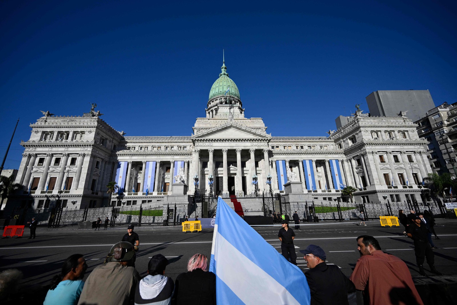 Apoiadores de Javier Milei aguardam a cerimônia de posse em frente ao prédio do Congresso — Foto: Luis ROBAYO / AFP