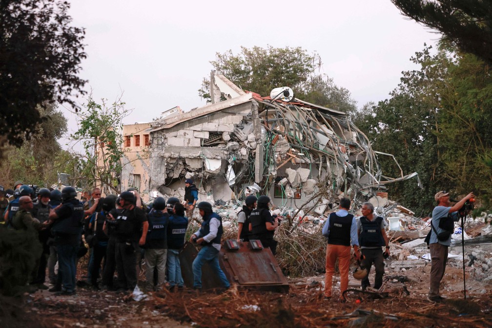 Jornalistas chegam a casa destruída no local da infiltração do fim de semana passado por militantes do Hamas no kibutz Beeri, perto da fronteira com Gaza — Foto: Menahem KAHANA/AFP