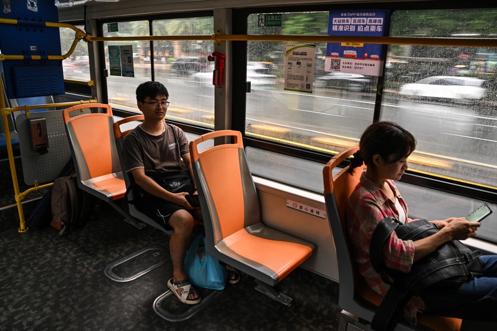 Passageiros viajam em um ônibus elétrico em Shenzhen: confortáveis e silenciosos — Foto: Hector Retamal/AFP