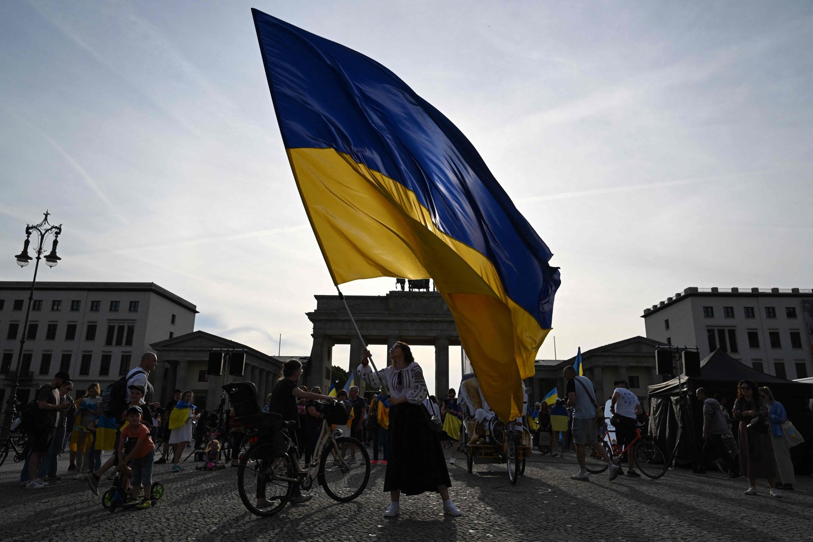 Jovem agita a bandeira nacional ucraniana em frente ao Portão de Brandemburgo, em Berlim, em 24 de agosto de 2023, durante um concerto para marcar o Dia da Independência da Ucrânia. — Foto: John MACDOUGALL / AFP
