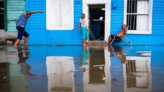 Um casal permanece fora de sua casa em uma área inundada de Batabano, província de Mayabeque, Cuba — Foto: Yamil LAGE/AFP