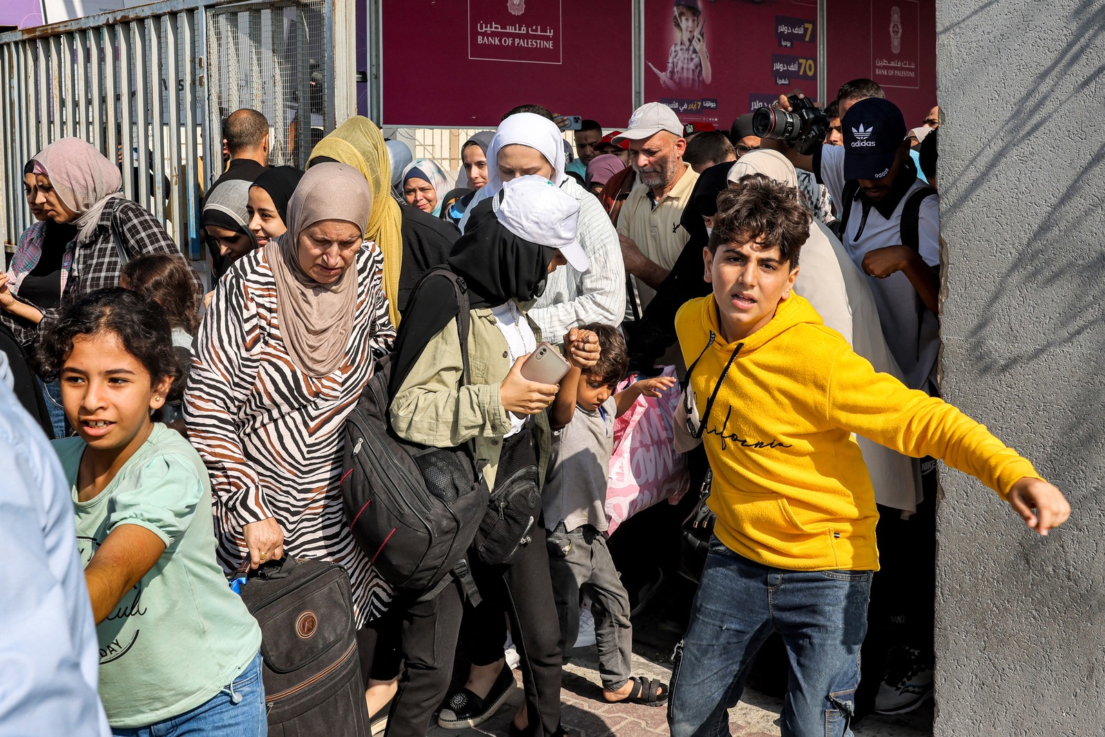 Pessoas atravessam um portão para entrar na passagem de fronteira de Rafah para o Egito, no sul da Faixa de Gaza — Foto: Mohammed ABED/AFP