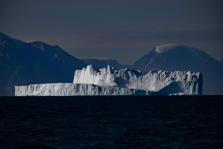 Um iceberg, com aproximadamente algumas centenas de metros de comprimento, à deriva ao longo do fiorde Scoresby Sound, no leste da Groenlândia.