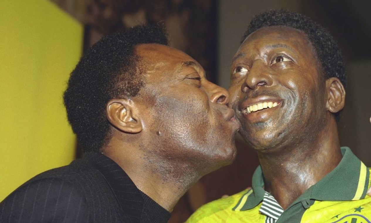 Pelé beija estátua dele mesmo, em exposição sobre sua vida na Casa França-Brasil  — Foto: Alexandre Cassiano / Agência O Globo