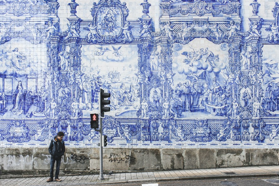 Homem espera sinal abrir em frente à igreja no Porto