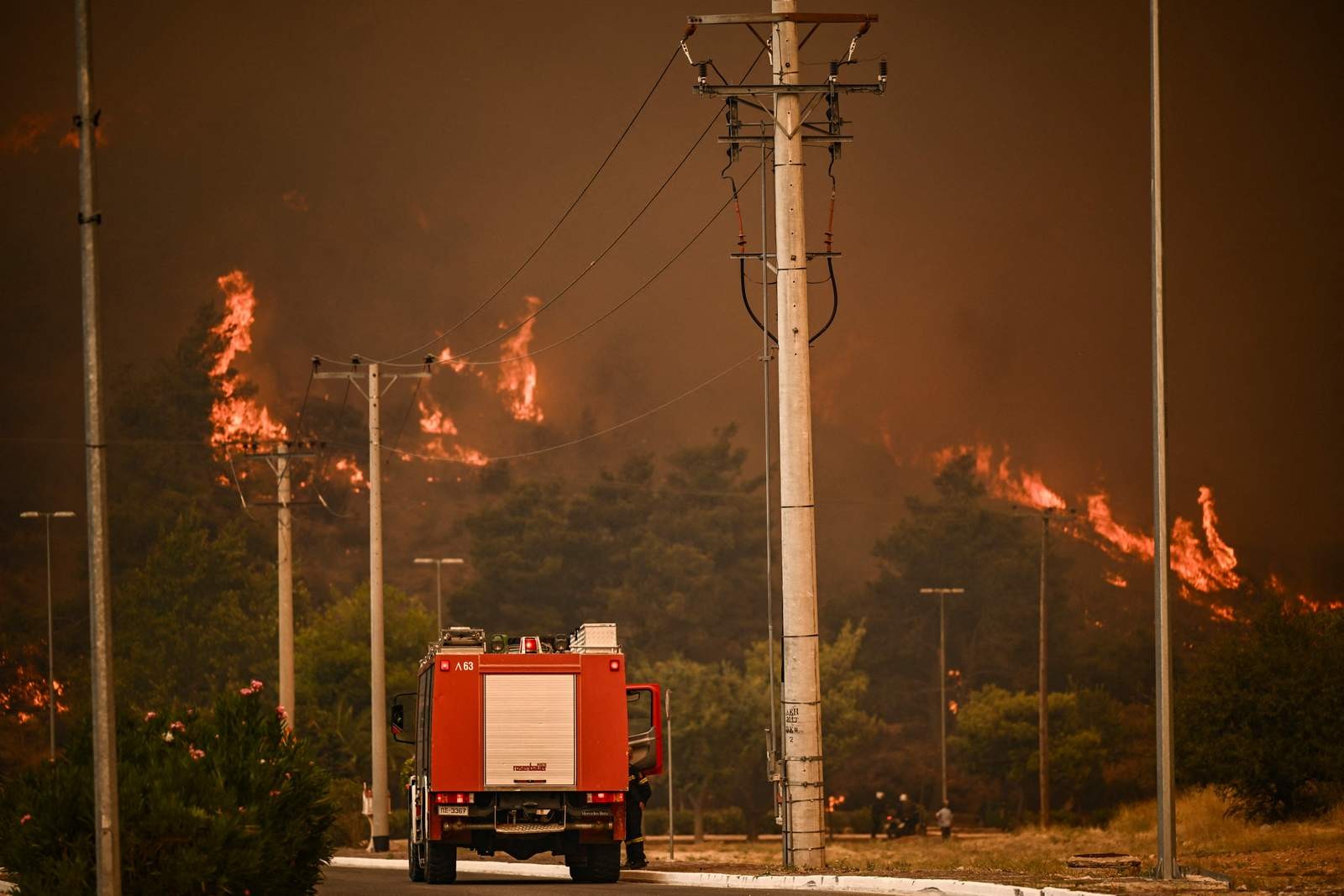 Um veículo de combate a incêndios circula em uma estrada durante um incêndio florestal em Chasia, nos arredores de Atenas — Foto: Angelos Tzortzinis / AFP