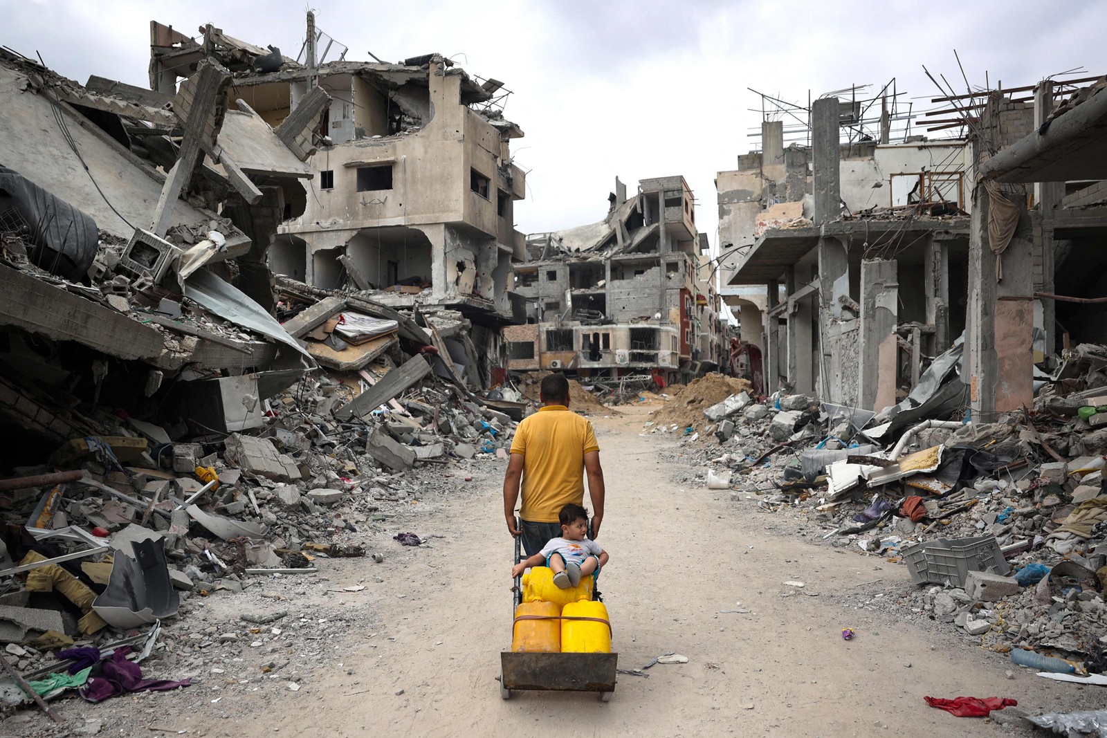 Palestinos em meio a edifícios destruídos em Khan Yunis, no sul da Faixa de Gaza — Foto: AFP
