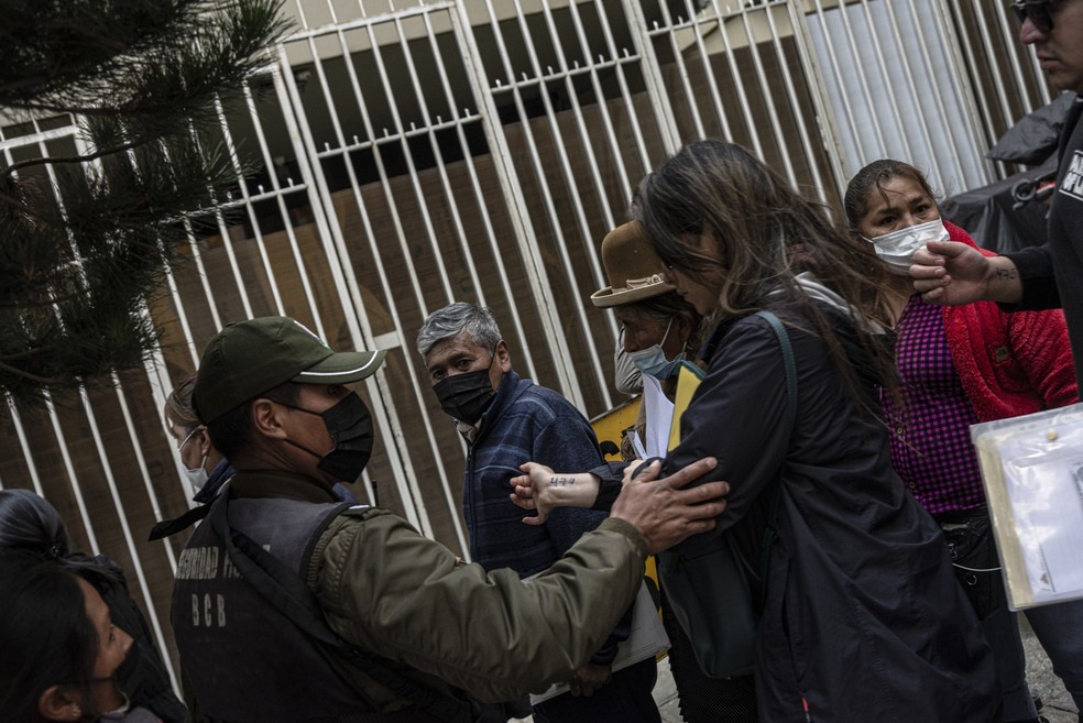 Mulher mostra a um policial a senha escrita em seu punho para tentar entrar na sede do Banco Central na tentativa de conseguir dólares — Foto: Bloomberg