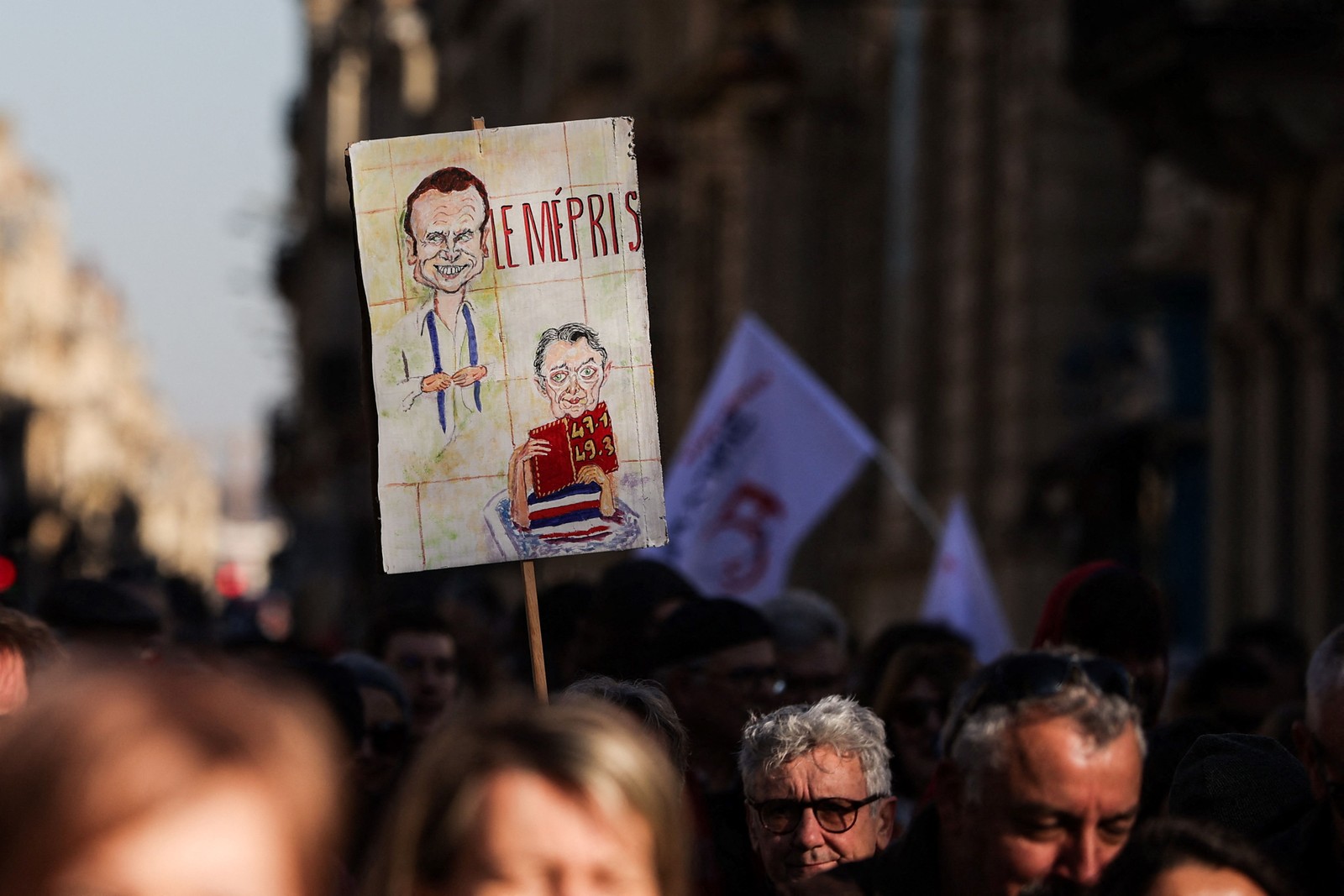 Manifestante segura um cartaz com a palavra "desprezo" e a caricatura de Emmanuel Macron enquanto marcha contra a reforma da Previdência — Foto: Thibaud Moritz/AFP