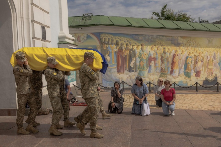 Pessoas se ajoelham enquanto soldados da Ucrânia carregam caixão de oficial morto na região de Donetsk