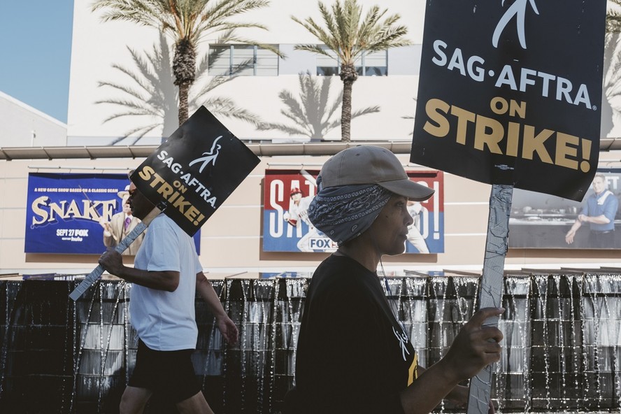 Atores com cartazes se manifestando durante a greve, em frente a estúdio em Los Angeles