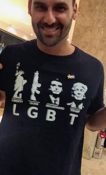 O deputado Eduardo Bolsonaro com uma camisa cuja estampa ironiza a sigla LGBT, utilizando as letras para exaltar os Estados Unidos, sua política de armamento, o presidente Jair Bolsonaro e o presidente americano, Donald Trump  — Foto: Reprodução