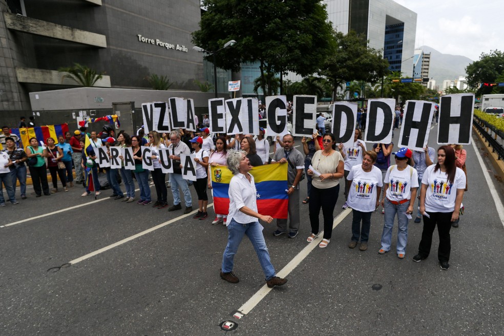 Oposição ao chavismo segura cartazes formando as palavras 'Venezuela exige Direitos Humanos' durante ato em 2019 — Foto: Cristian Hernandez/AFP