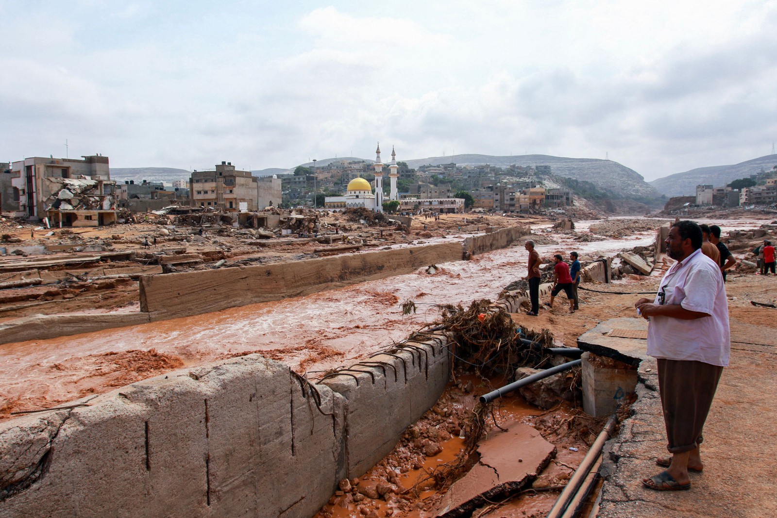 As pessoas olham para os danos causados ​​pelas inundações estranhas em Derna, no leste da Líbia — Foto: AFP