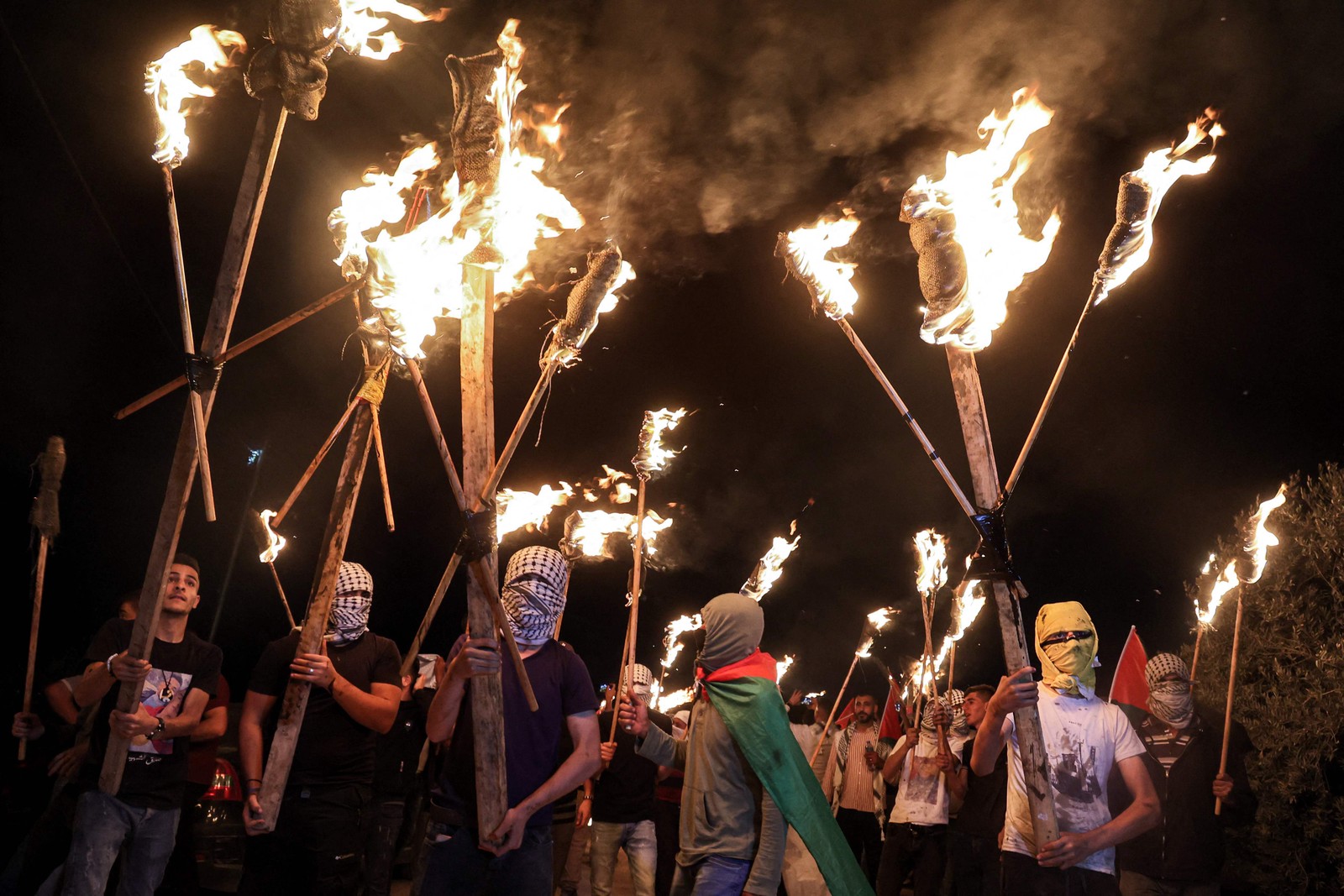 Manifestantes palestinos marcham com tochas contra o posto avançado dos colonos israelenses de Eviatar, na cidade de Beita, na Cisjordânia. O governo de Israel chegou a um acordo para colonos judeus para desocupar o posto avançado ilegal da CisjordâniaAFP