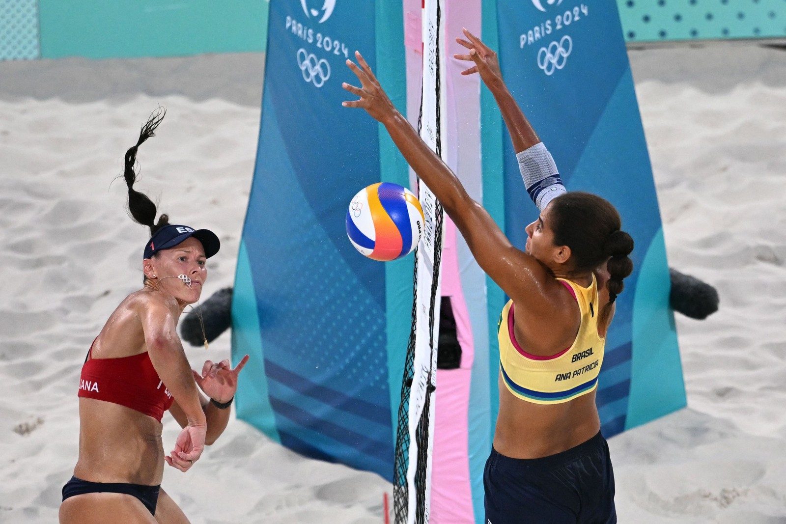 A número 01 da Espanha, Liliana Fernandez Steiner (E), crava a bola enquanto a número 01 do Brasil, Ana Patricia Silva Ramos, bloqueia na piscina feminina. Uma partida de vôlei de praia entre Brasil e Espanha durante os Jogos Olímpicos de Paris 2024 no Estádio da Torre Eiffel, em Paris, em 30 de julho de 2024 — Foto: Kirill KUDRYAVTSEV / AFP