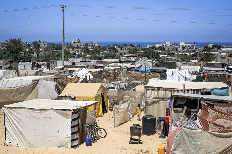 Uma menina caminha fora de uma tenda em um campo para pessoas deslocadas pelo conflito em Khan Yunis, no sul da Faixa de Gaza, em 11 de julho de 2024, em meio ao conflito contínuo no território palestino entre Israel e Hamas