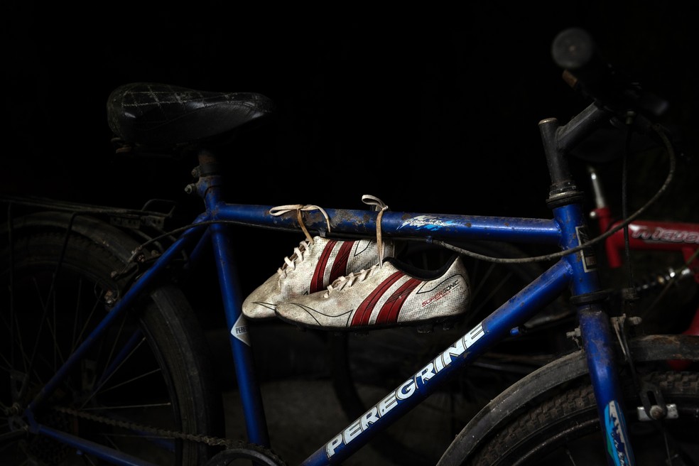 Um par de chuteiras e uma bicicleta usada por um dos membros do time de futebol Wild Boars para ir até a caverna Tham Luang em junho de 2018 é exibido na entrada do parque — Foto: Luke Duggleby/The New York Times