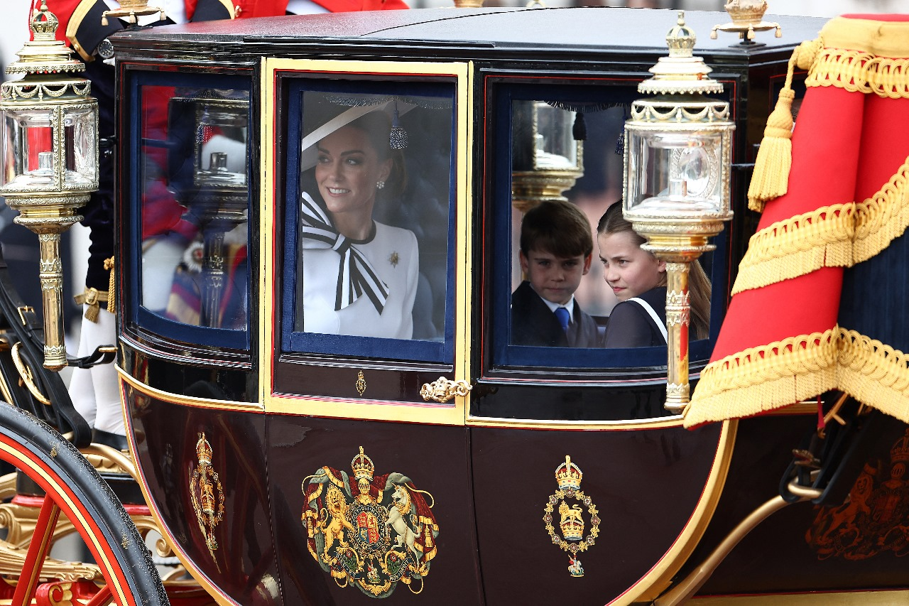 Kate Middleton sorri ao lado dos filhos, a princesa Charlotte e o príncipe Louis, a caminho do Desfile de Aniversário do Rei em Londres — Foto: HENRY NICHOLLS/AFP