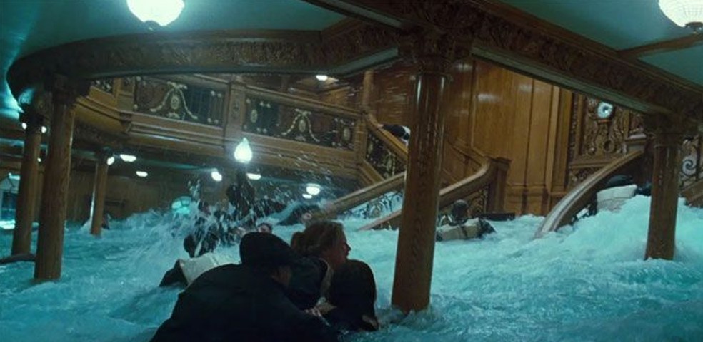Cena do filme Titanic em que a escadaria no salão principal do navio é inundada — Foto: Reprodução